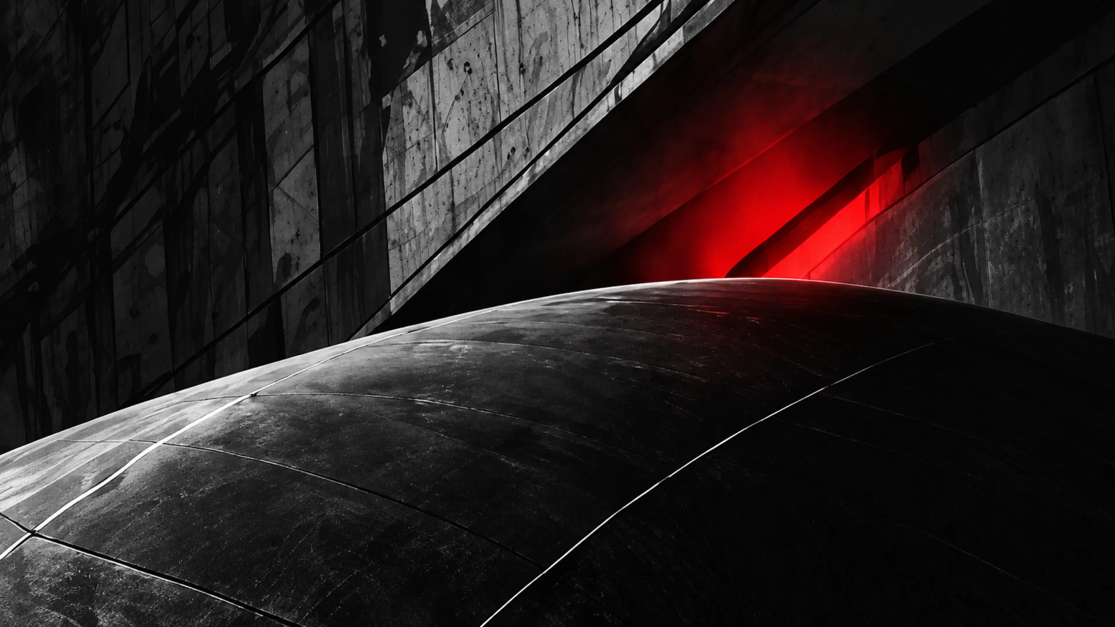 Une courbe de béton sous une lumière rouge rasante.