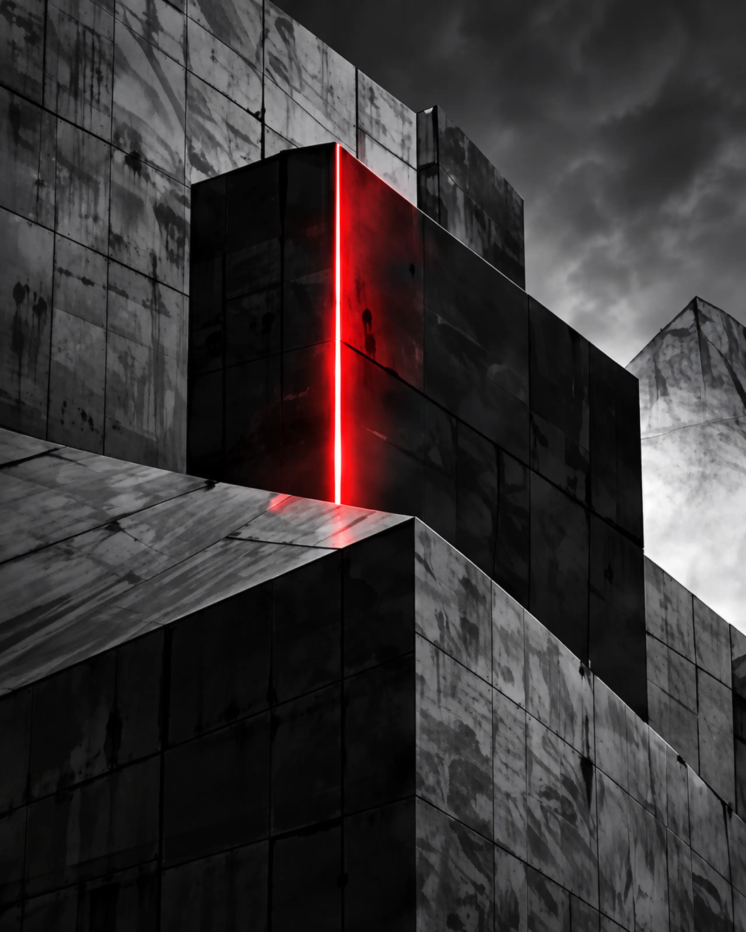 Un bloc architectural noir fendu de rouge, sous un ciel gris.